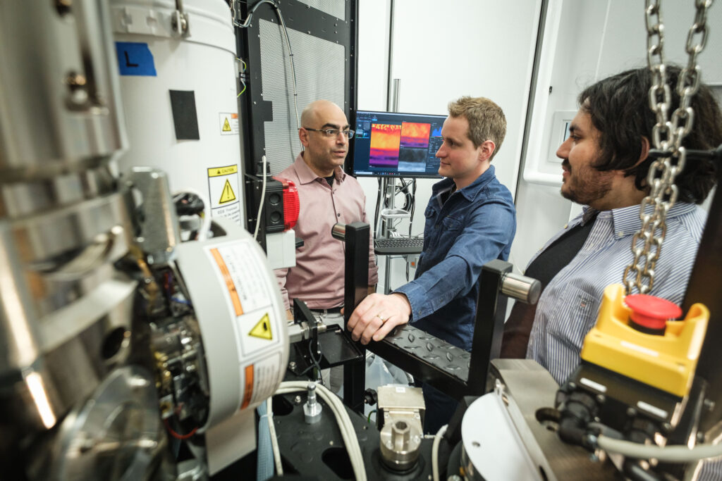Vue de près du microscope électronique en transmission, trois personnes en arrière-plan