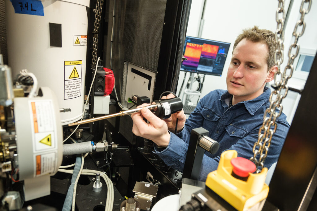 Un associé de recherche insère un échantillon dans le microscope électronique en transmission
